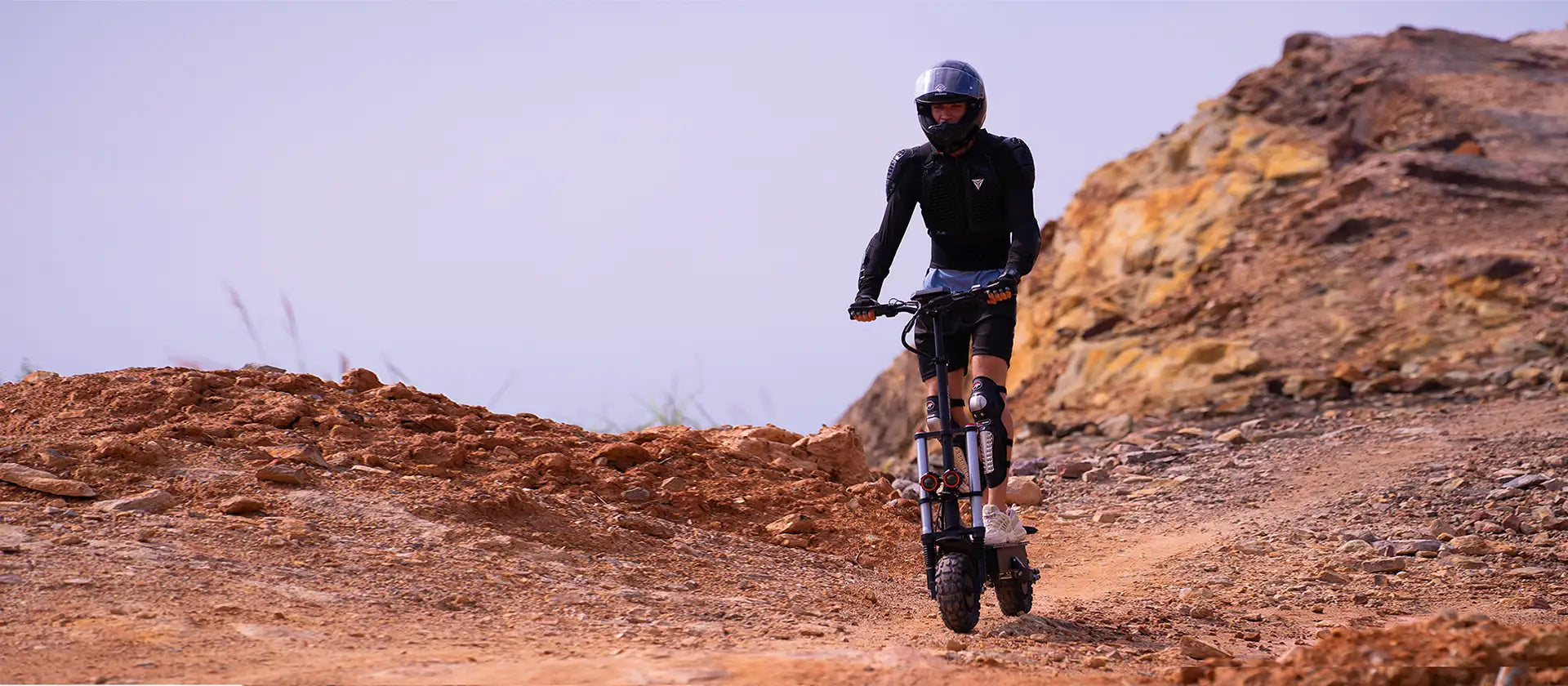 Rider on ONECNA electric scooter on desert off-road terrain — comparing 12-inch vs 10-inch wheel electric scooters